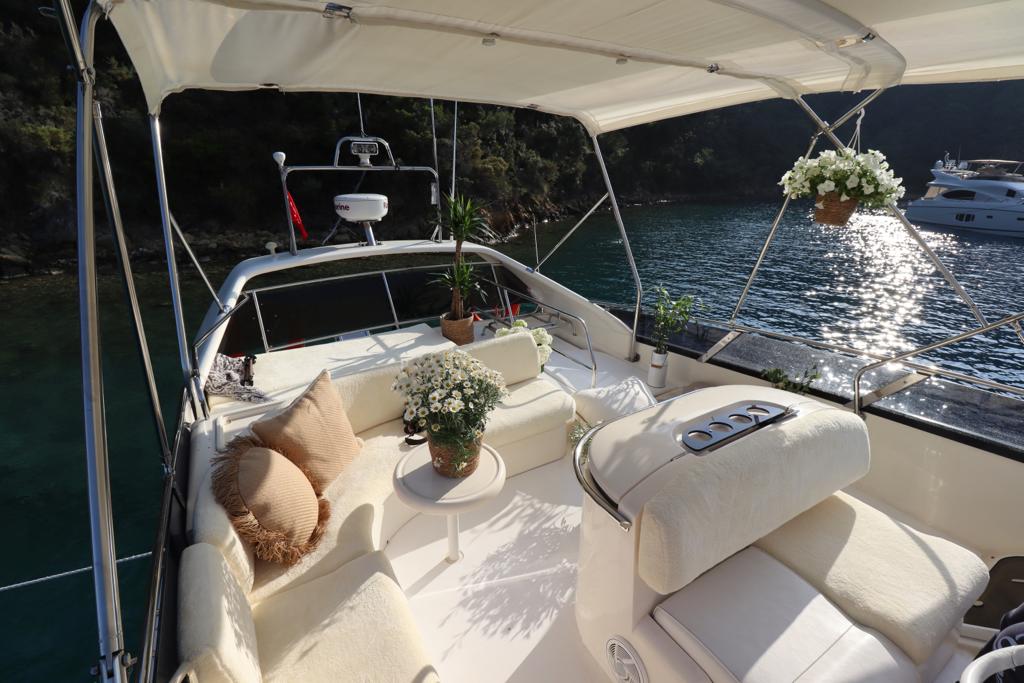 Een gestroomlijnd luxe motorjacht dat door het kristalheldere turquoise water van de twaalf eilanden van Göcek vaart, omringd door met pijnbomen bedekte bergen.