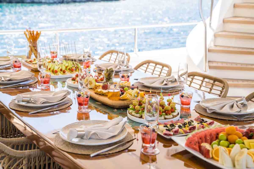 Κοντινό πλάνο θαλασσινών υψηλής ποιότητας και σαμπάνιας που σερβίρεται από μέλος του πληρώματος.
