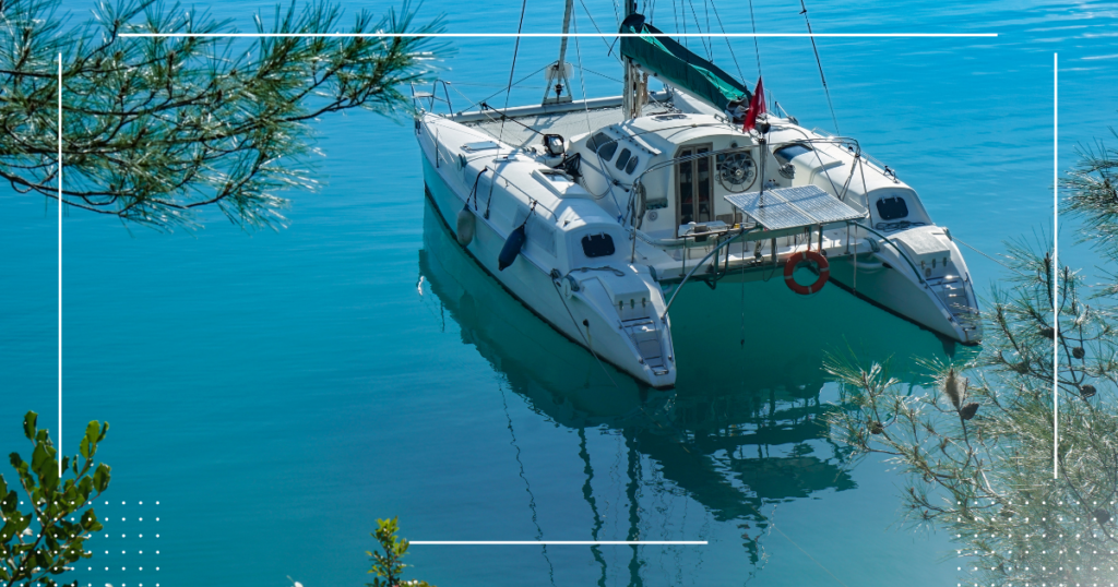 Catamaran yacht anchored in shallow waters very close to a pine tree shoreline in turkey.